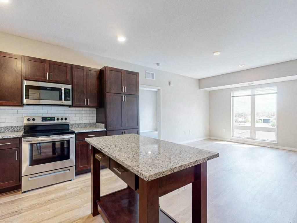 an empty kitchen with a granite island in the middle