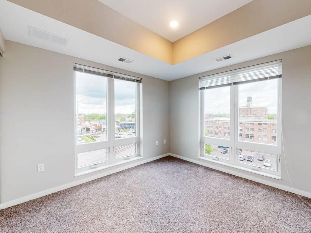 an empty living room with three windows and a view of the city