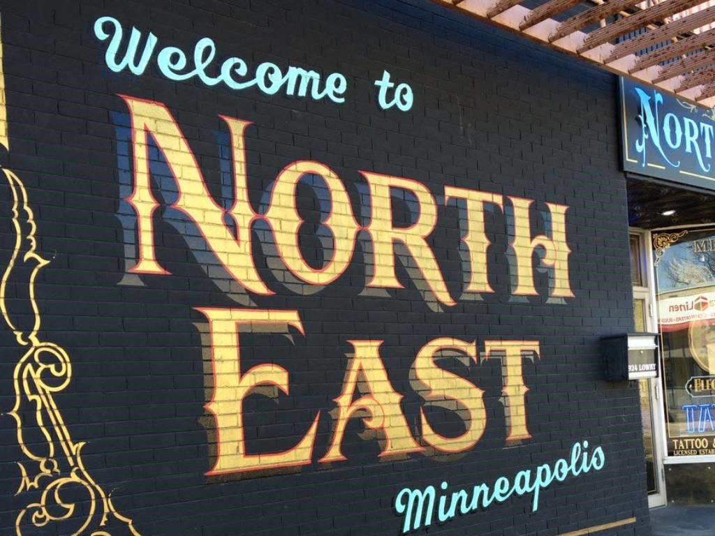a sign that says north east on a brick wall