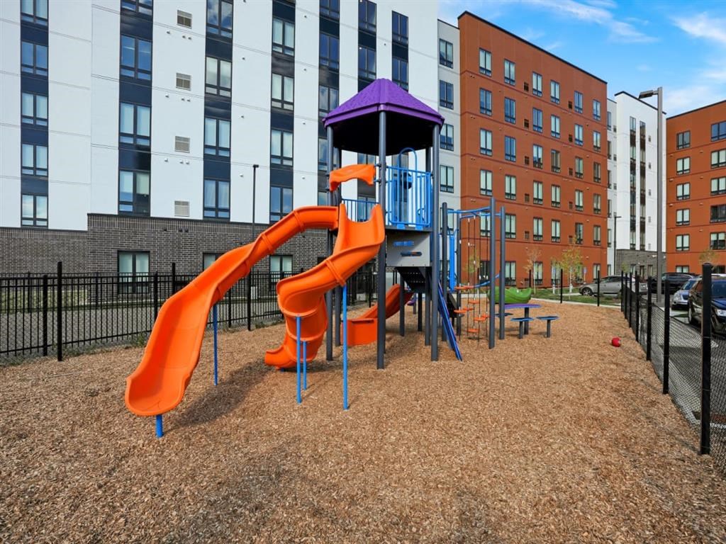 a playground with a slide and a picnic table in front of a building