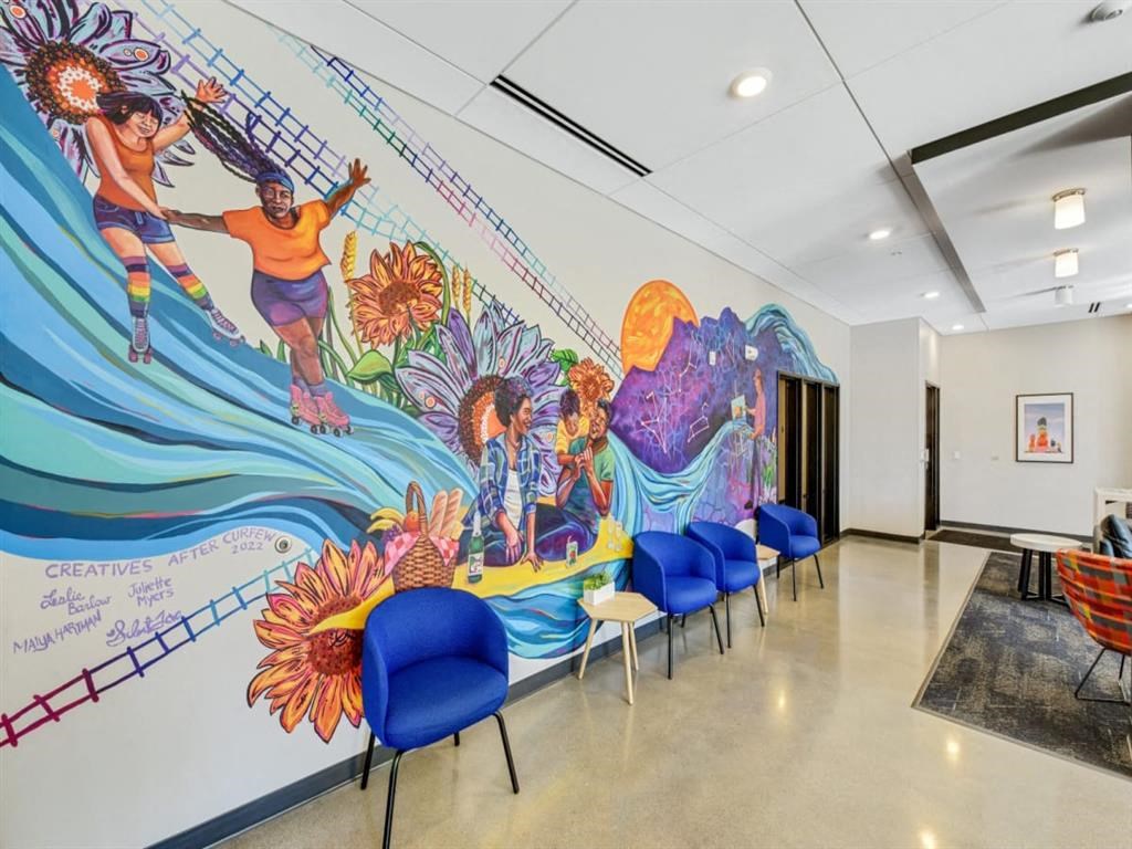 a mural in a hallway with blue chairs