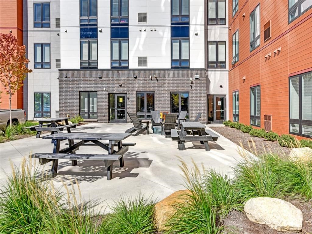 a courtyard with picnic tables and benches in front of a building