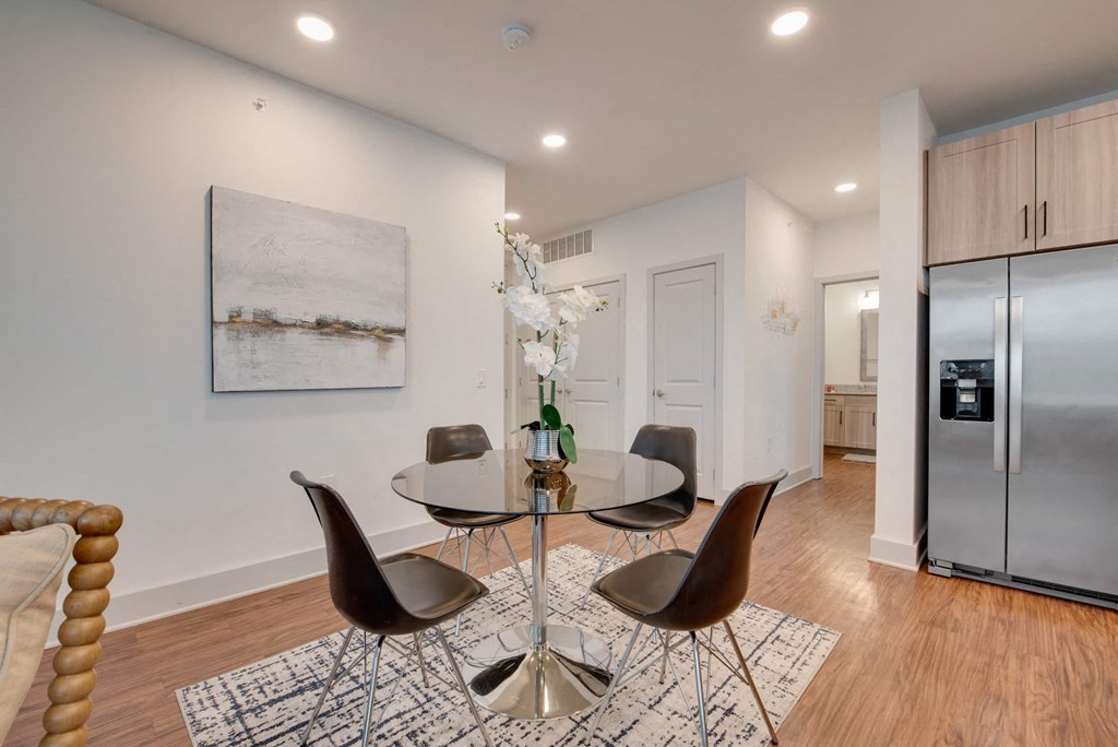 a dining room with a glass table and chairs and a stainless steel refrigerator