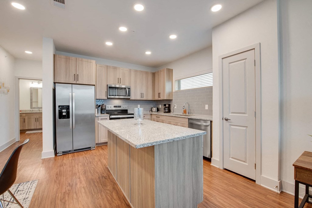 a kitchen with a large island and a stainless steel refrigerator