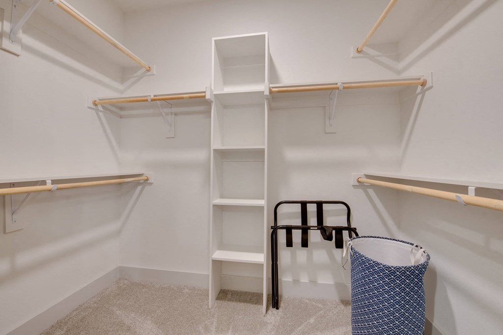 a walk in closet with shelves and a stool