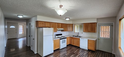 an empty kitchen with white appliances and wooden cabinets