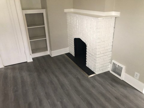 the living room with the fireplace and the wood floor