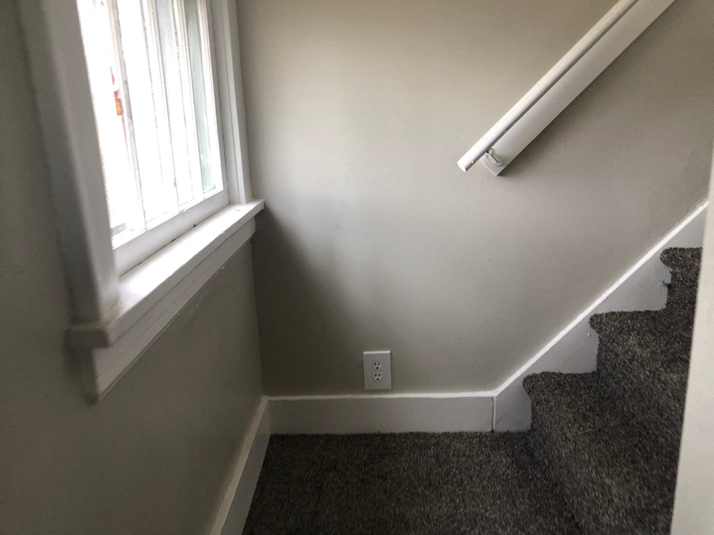 the corner of a room with a window and carpeted stairs