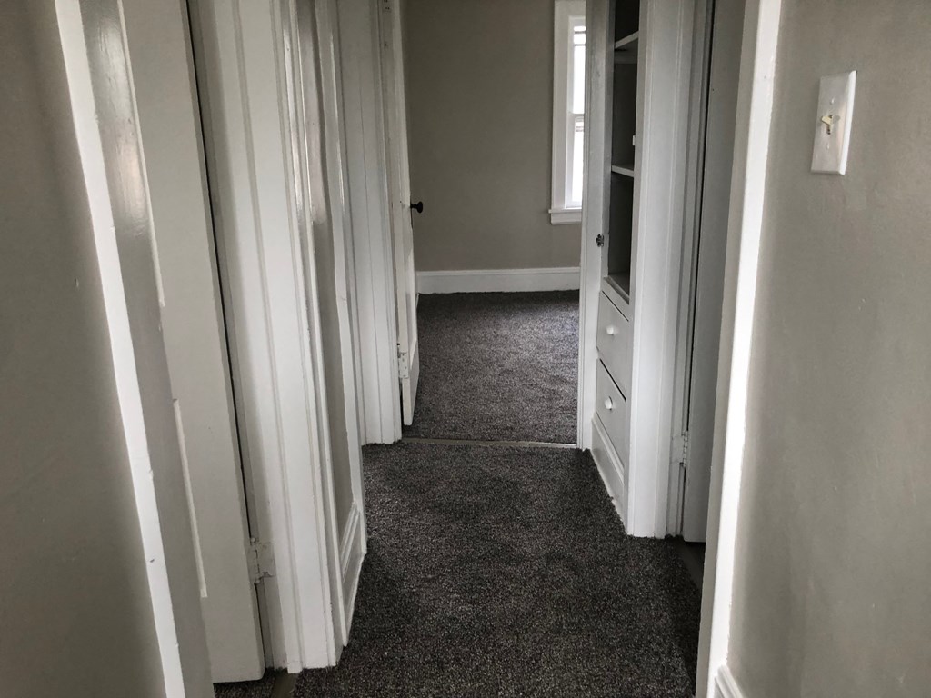 a room with a carpeted floor and a hallway with open doors