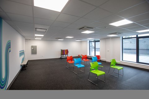 A room with a row of chairs and a white wall with a blue design.