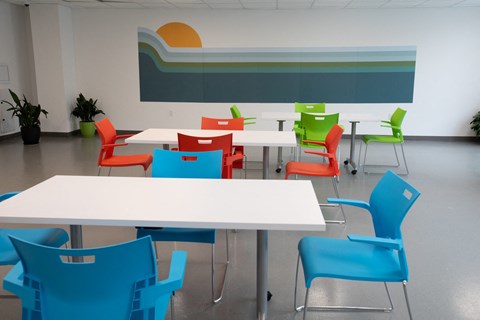A white table surrounded by red and blue chairs in a room.