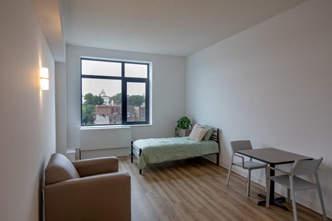 A bedroom with a bed, chair, and table.
