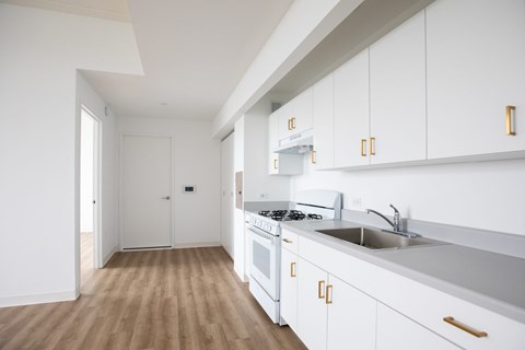 A kitchen with white cabinets and a stove top oven.
