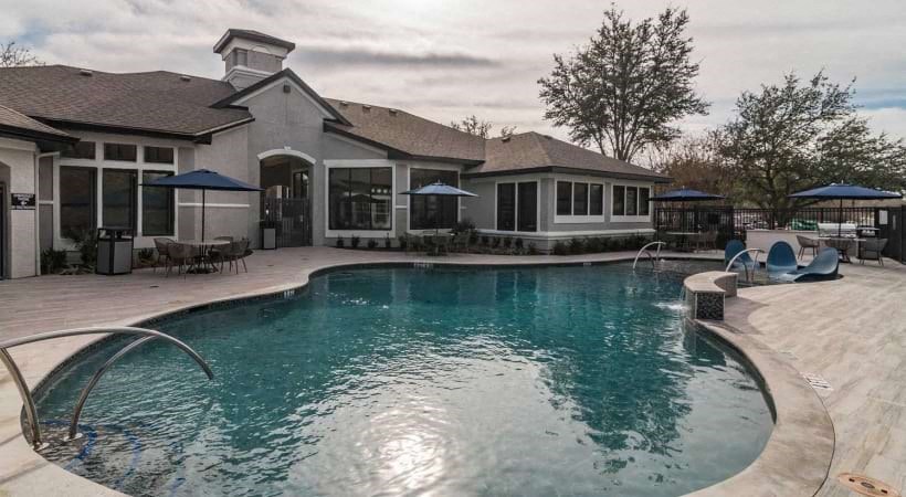 a large swimming pool with a house in the background