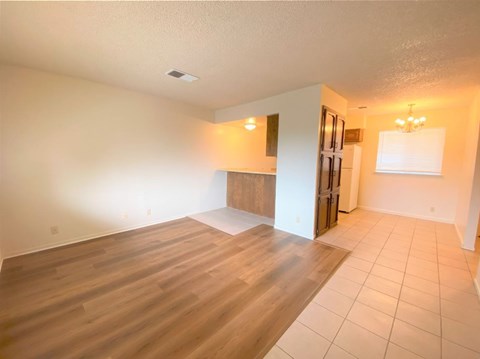 an empty living room and kitchen with wooden floors