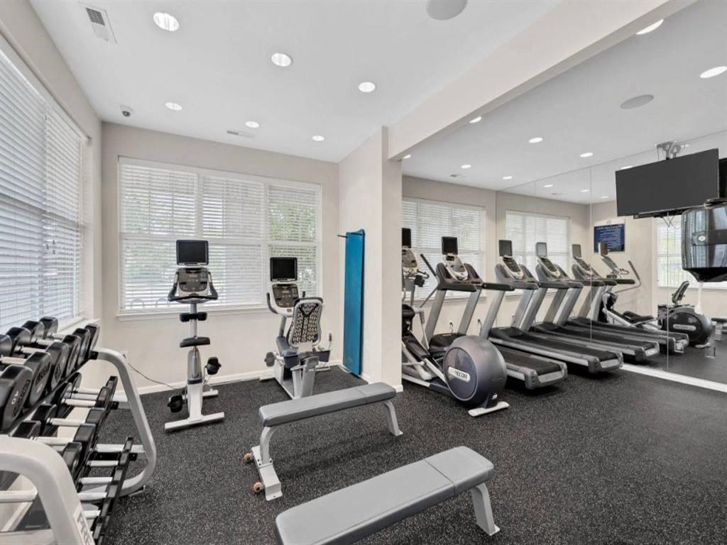 a gym with rows of exercise equipment and a tv