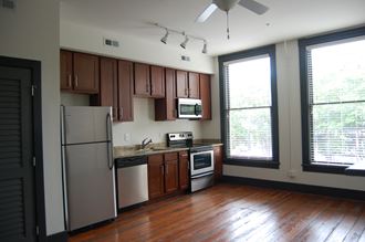 an empty kitchen with wood floors and stainless steel appliances