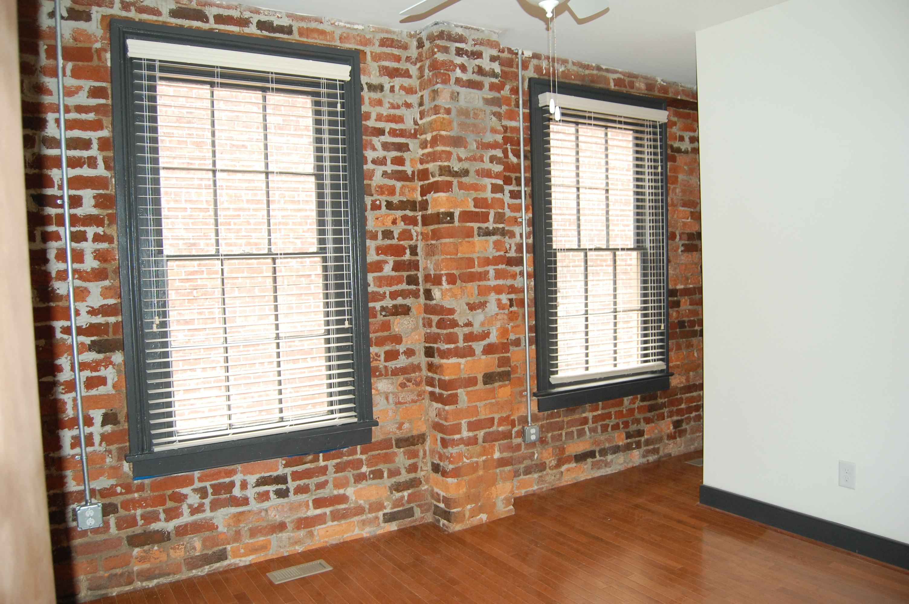 a brick wall in a room with two windows