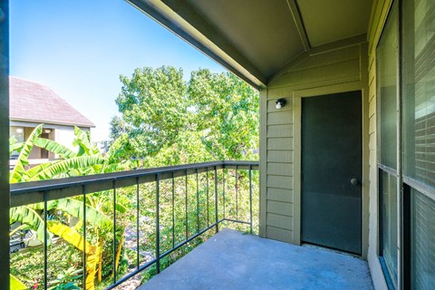 A balcony with a black railing and a grey door.