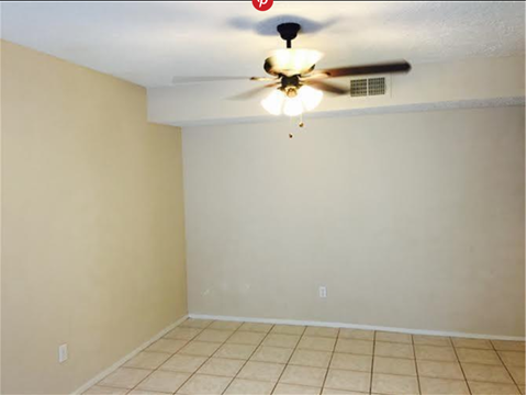 A room with a ceiling fan and tile flooring.