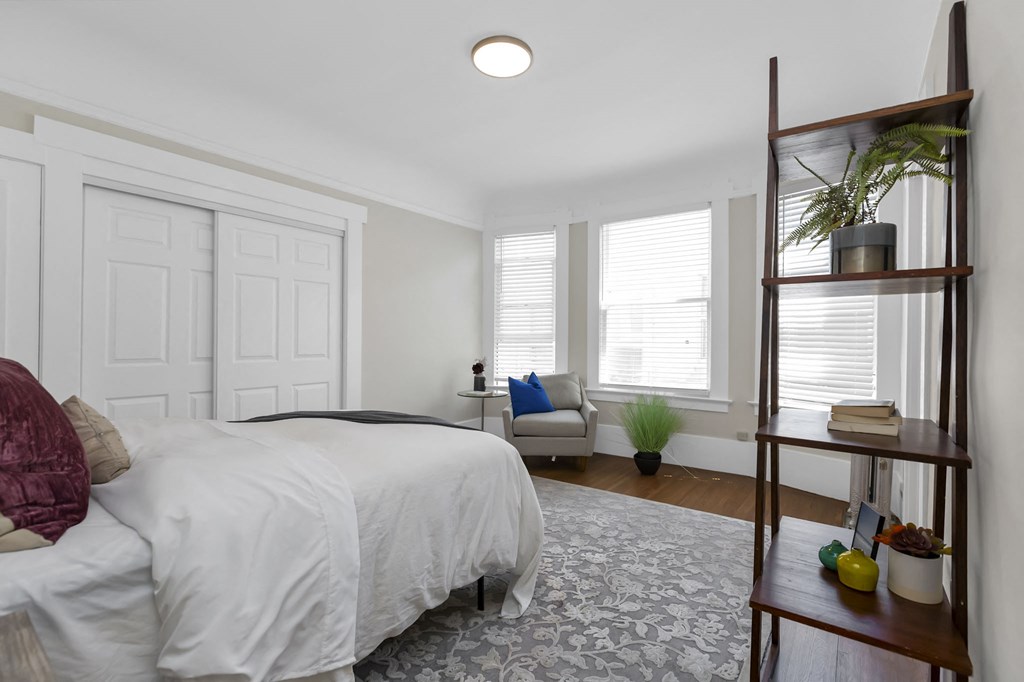 a bedroom with white walls and a bed with a white comforter