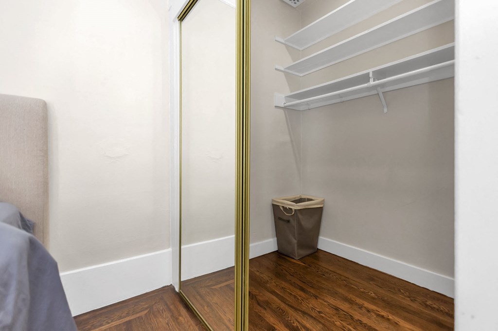 a closet in a bedroom with a trash can on the floor