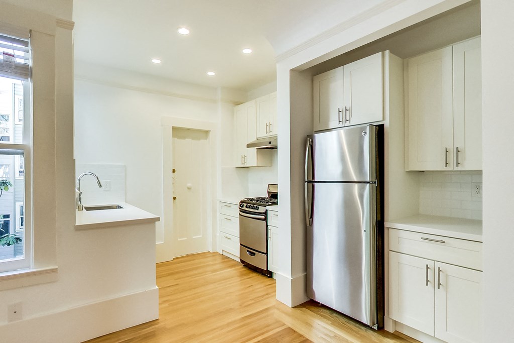 a kitchen with white cabinets and a stainless steel refrigerator