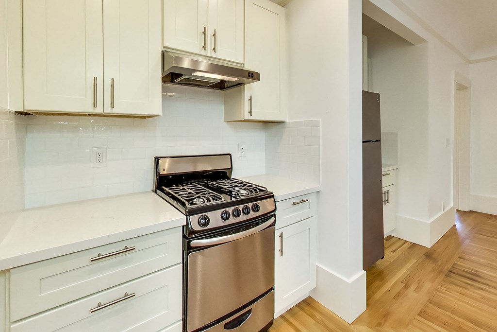 a kitchen with white cabinets and a stainless steel stove