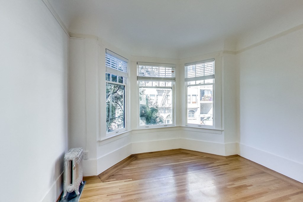 a living room with three windows and a wood floor