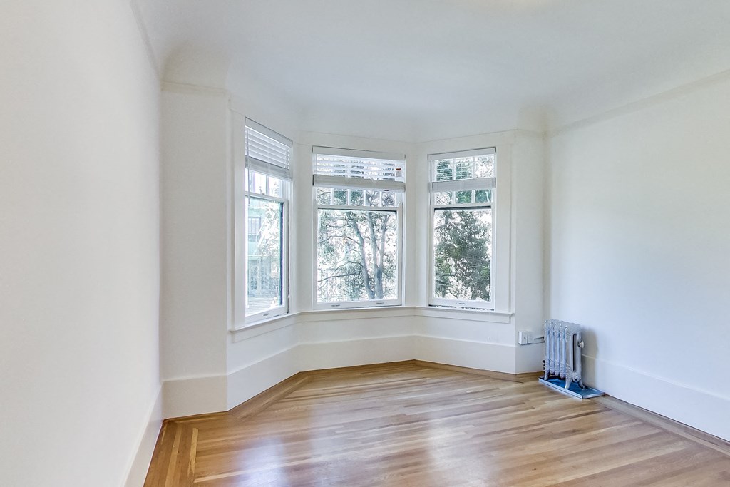 an empty room with three windows and a wood floor