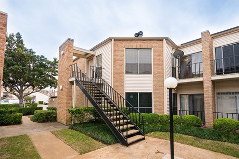 A brick house with a black staircase leading to the second floor.