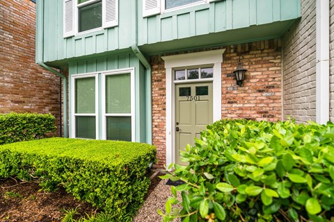 A green house with a white door and windows.