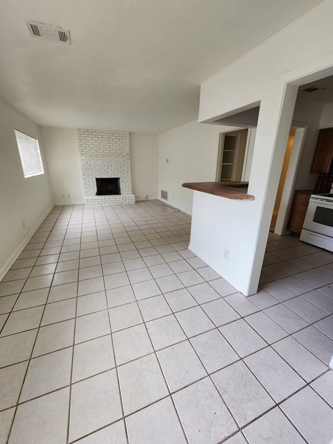 an empty living room with a tiled floor and a fireplace