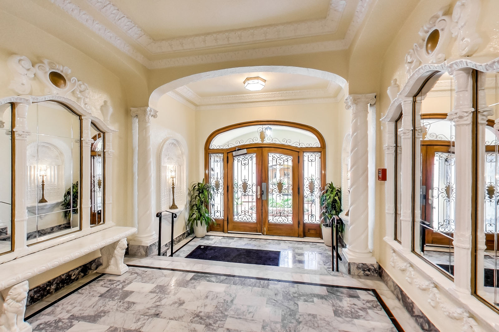 A hallway with a marble floor and a large wooden door.