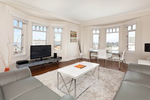 A living room with a grey couch, a white coffee table, and a television.