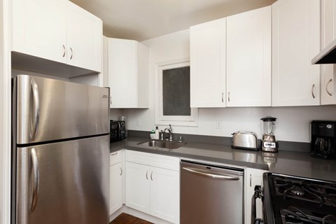 A modern kitchen with white cabinets and stainless steel appliances.