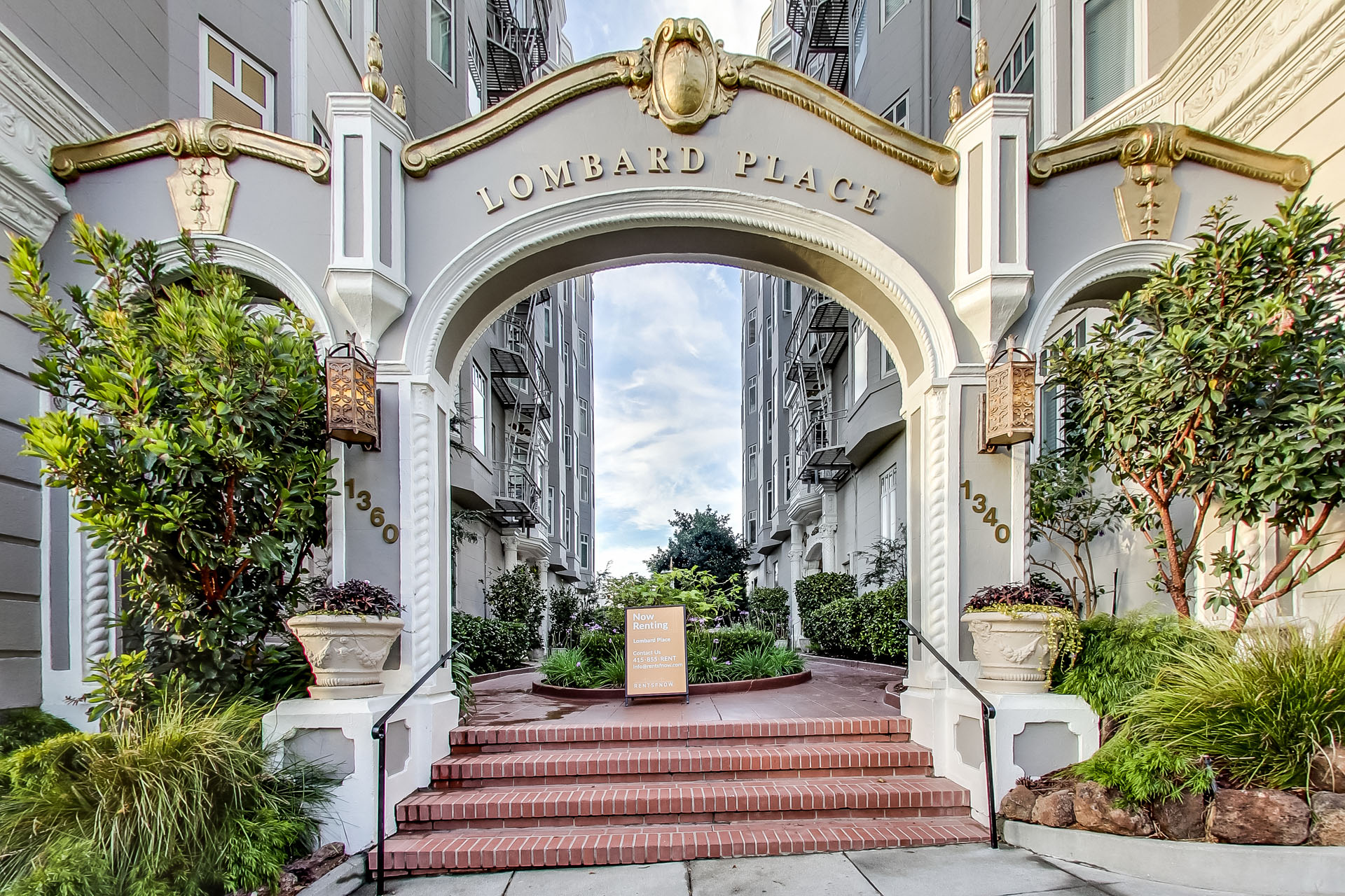A white building with a red staircase leading to a sign that says "Lombard Place".
