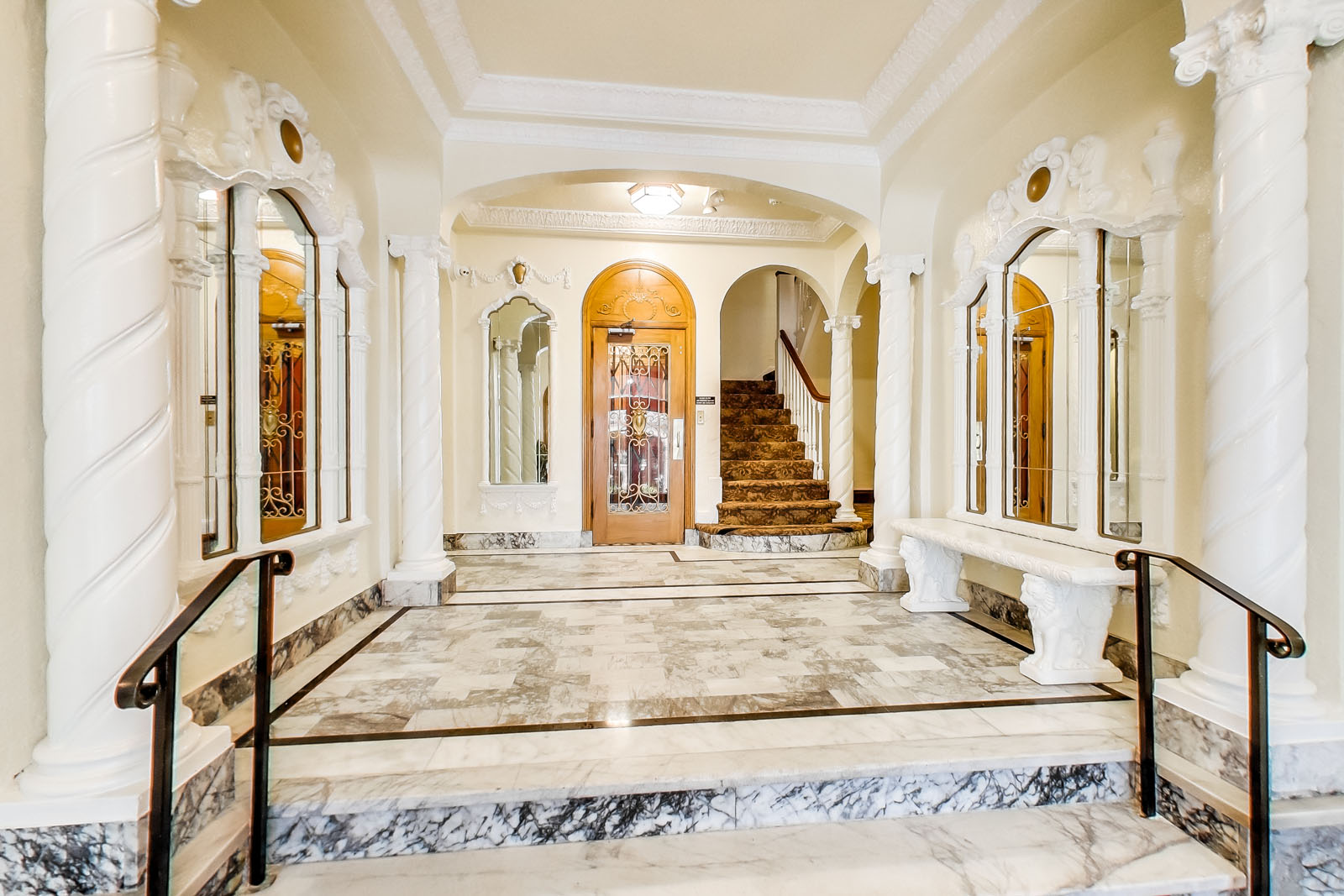 A grand staircase with a marble floor and white columns.