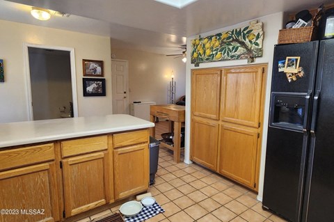 a kitchen with wooden cabinets and a black refrigerator