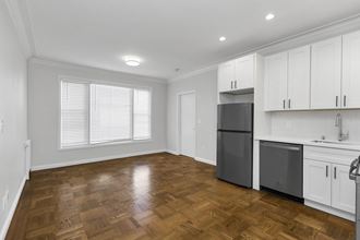 an empty kitchen with white cabinets and a stainless steel refrigerator