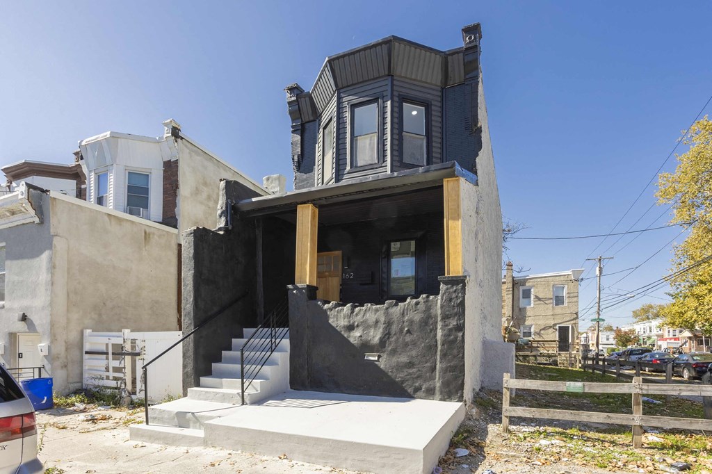 A modern house with a black exterior and a large window.