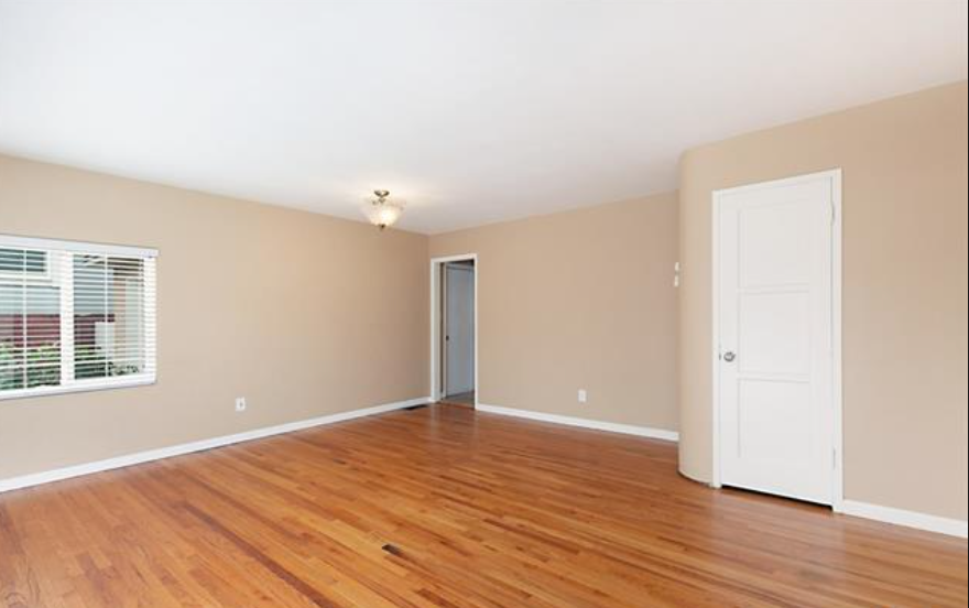 an empty living room with wood floors and a white door