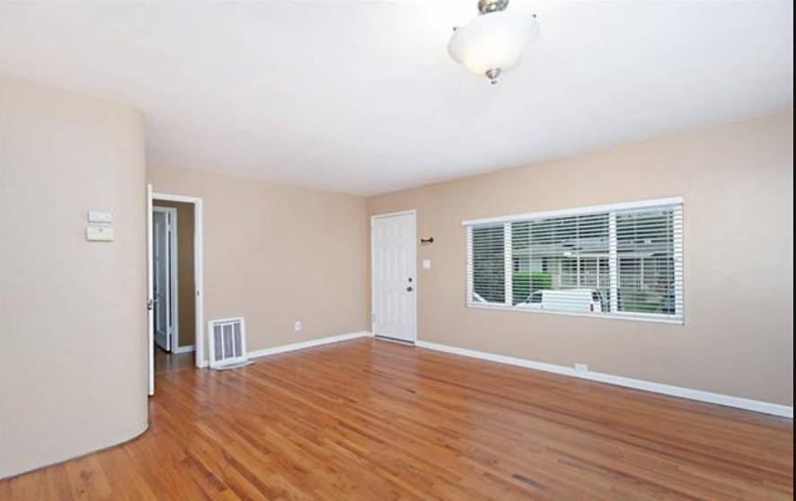 an empty living room with wood floors and a window