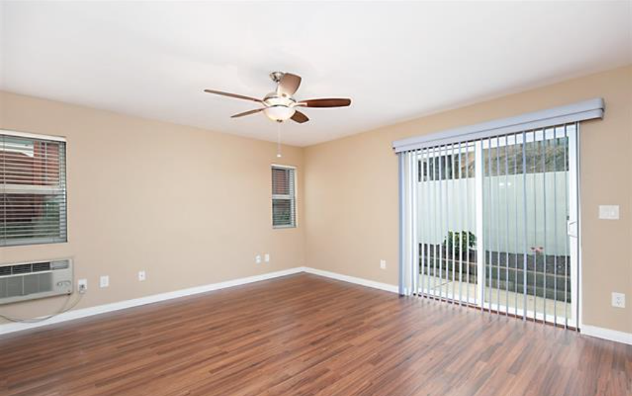 an empty living room with a ceiling fan and a window