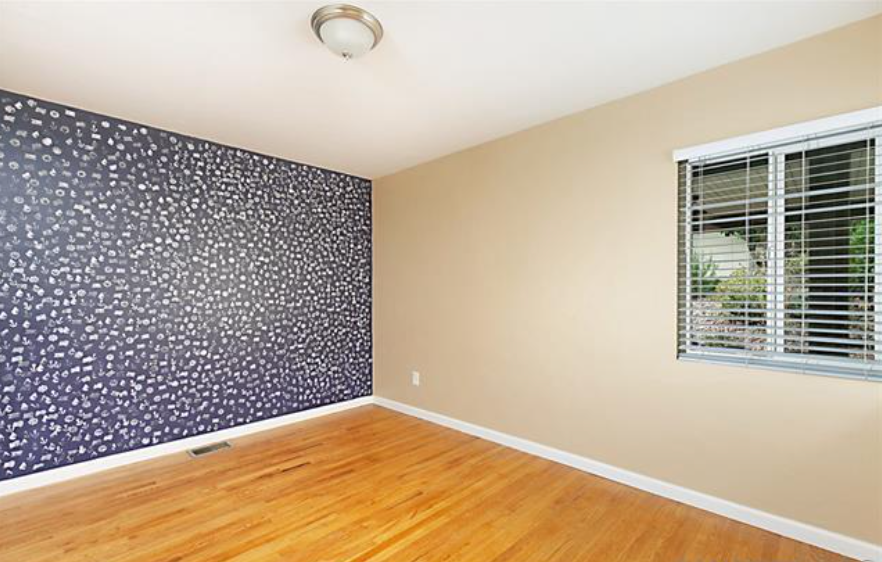 an empty room with a window and a hard wood floor
