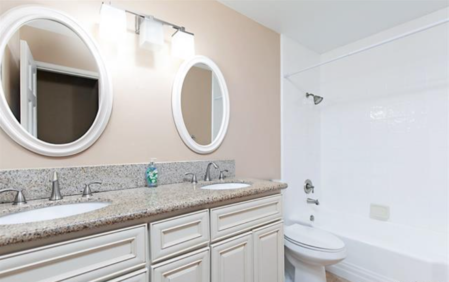 a bathroom with two mirrors and two sinks and a toilet