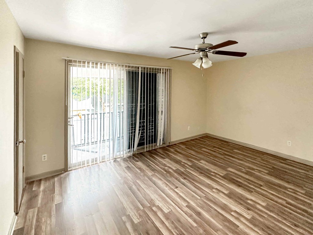 an empty living room with wood flooring and a ceiling fan