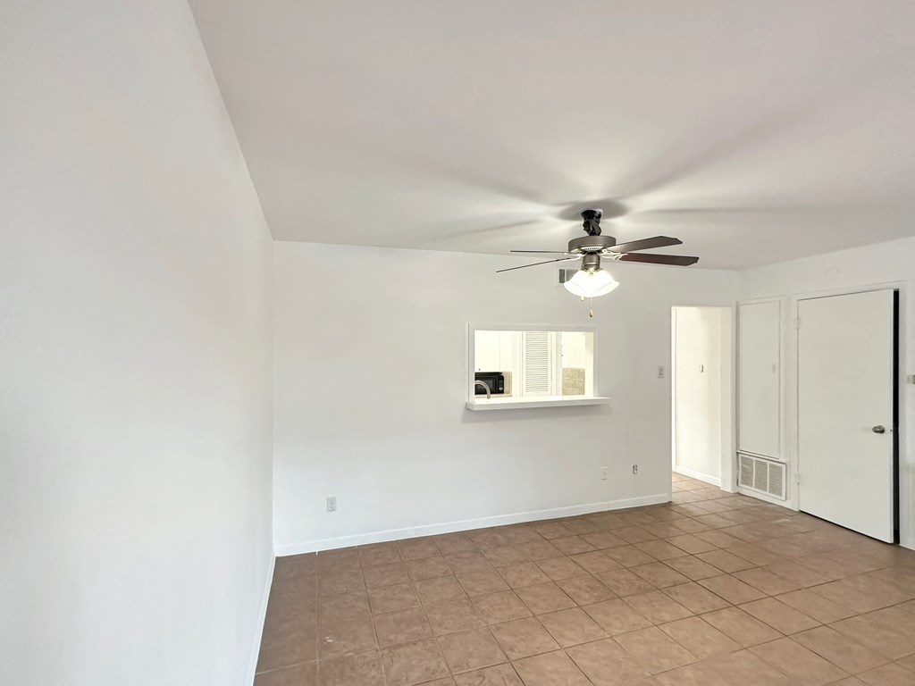 an empty living room with a ceiling fan and a window