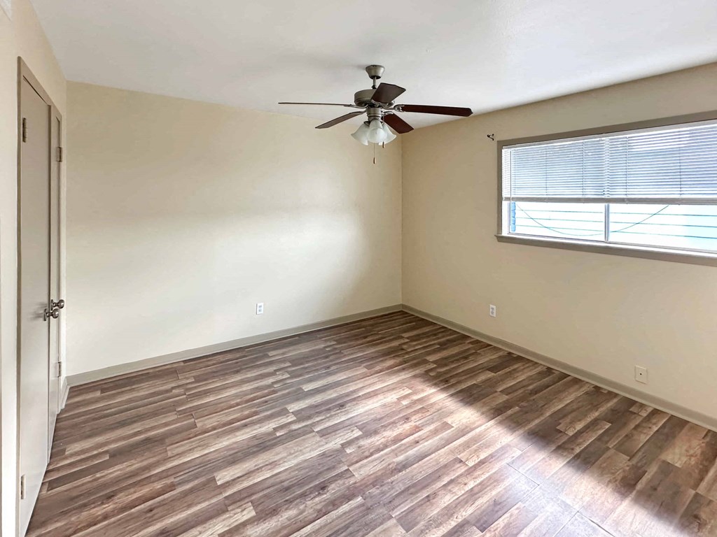 an empty bedroom with a ceiling fan and a window