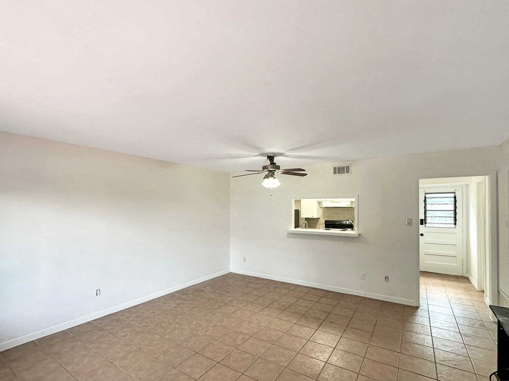 an empty living room with a ceiling fan